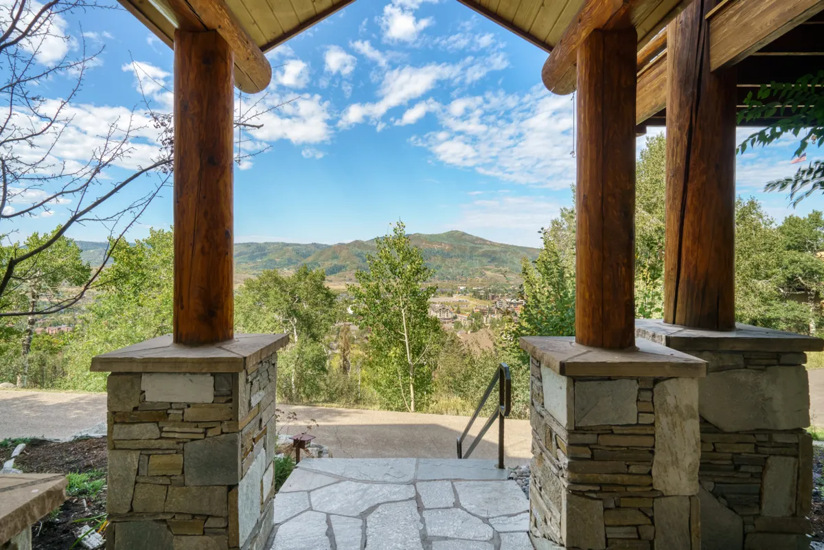 A serene shot of the home's wooden columns and stone pillars, opening up to a breathtaking mountain view. The porch setting invites guests to relax, soak in the scenery, and feel connected to Steamboat’s natural surroundings.