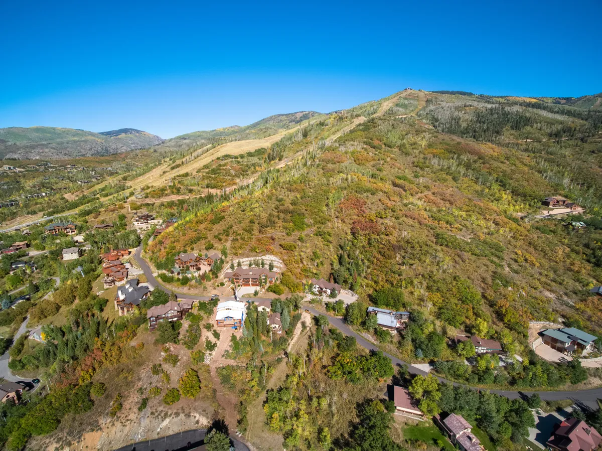 A sweeping exterior view of Steamboat's mountain landscape with colorful foliage and residential buildings nestled among the trees. The scene is imbued with a serene, adventurous atmosphere and hints at year-round outdoor activities such as hiking, biking, and exploring the mountains.