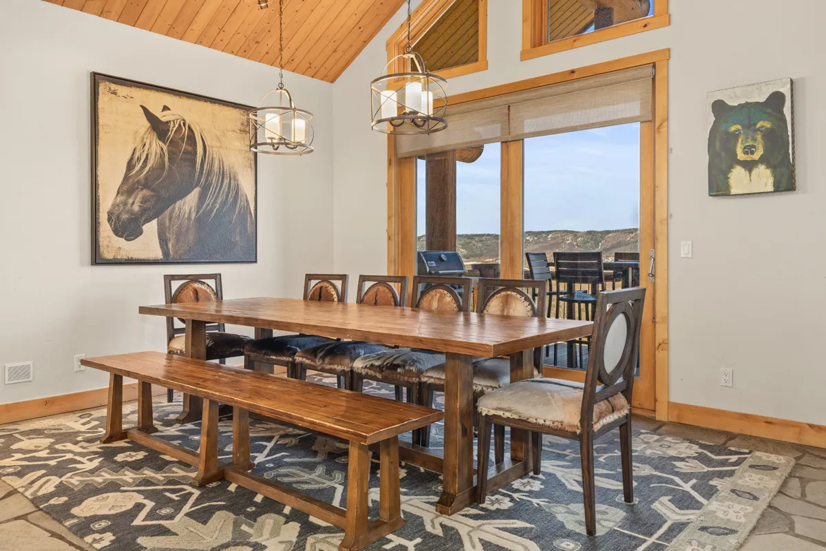 This image spotlights the elegant dining area, featuring a large wooden table that comfortably seats 12, enhanced by artistic touches like horse and bear paintings and a statement chandelier. The setting is perfect for festive group meals and intimate celebrations.