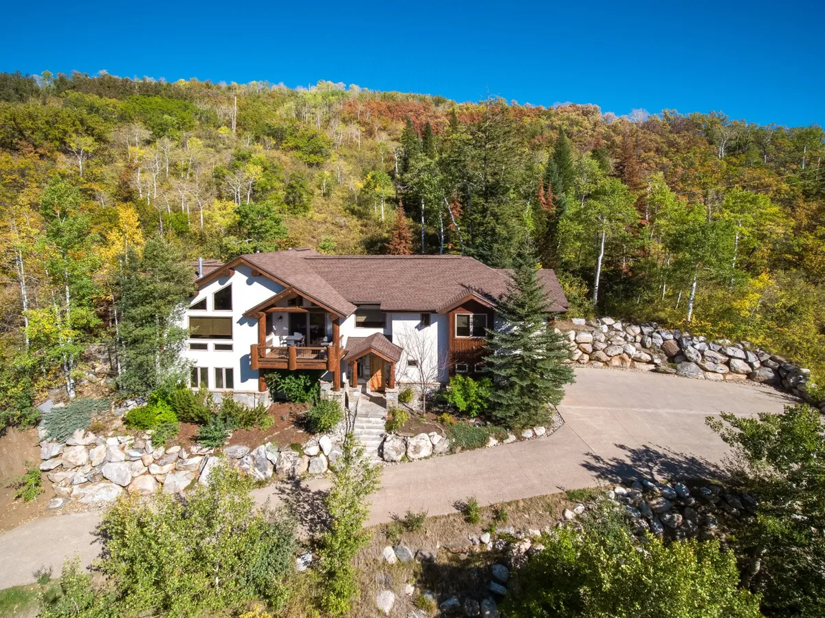 The main entrance of the chalet, framed by stone landscaping and lush surrounding trees and foliage. The peaceful, welcoming mood invites visitors to imagine arriving at a home base for their Steamboat Springs explorations.